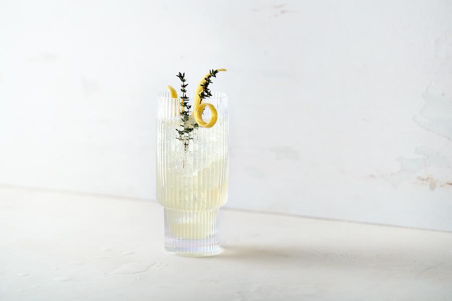 Nona June Collins - alcoholvrije cocktail. Een longdrinkglas gevuld met deze alcoholvrije cocktail en gegarneerd met een citroenschil en takje tijm.