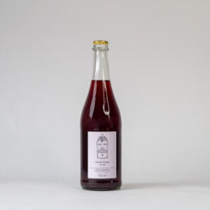 Een fles Cuvée Cassy Botanical Wyne. Een lichtroze etiket met een foto van een kleine totempaal, Cuvée Cassy is rood van kleur en de fles wordt afgesloten met een kroonkurk