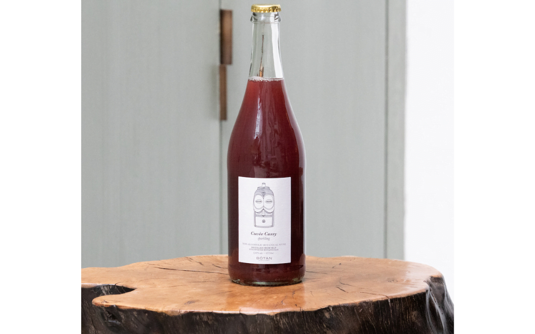 Een fles alcoholvrije Cuvée Cassy Sparkling op een houten schijf