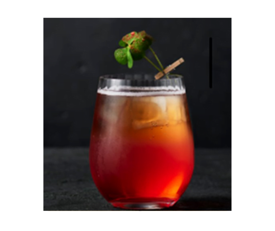 Een sfeervol glas met de alcoholvrije cocktail Flower of Jasminum. Het geheel heeft de sfeervolle kleur van thee en is gegarneerd met een takje jasmijn.